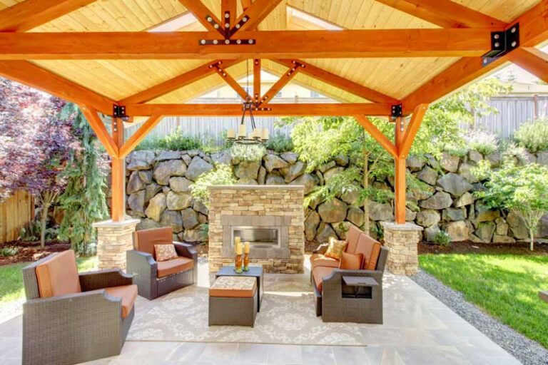 A wood patio cover over an outdoor living area with a stone fireplace